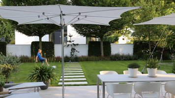 Designergarten mit Terrasse, Sonnenschirm und Möbeln